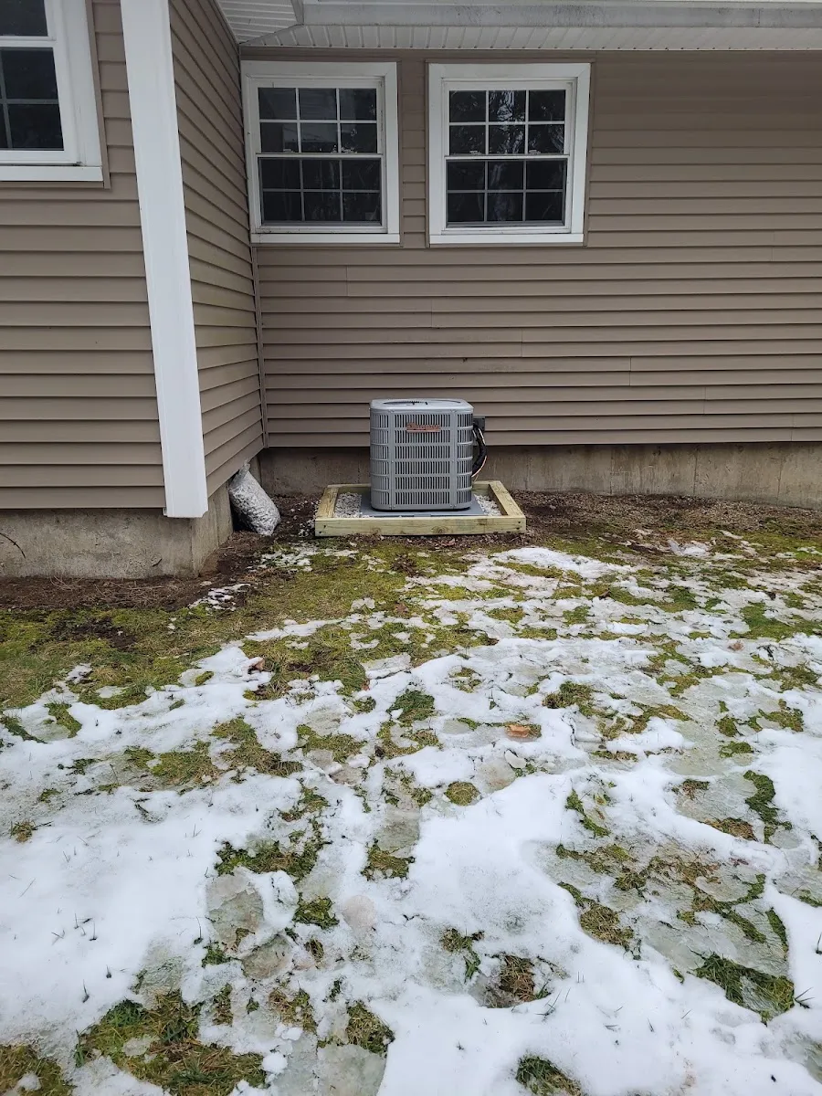 Central air conditioning condenser unit installed on a pad beside a Connecticut home